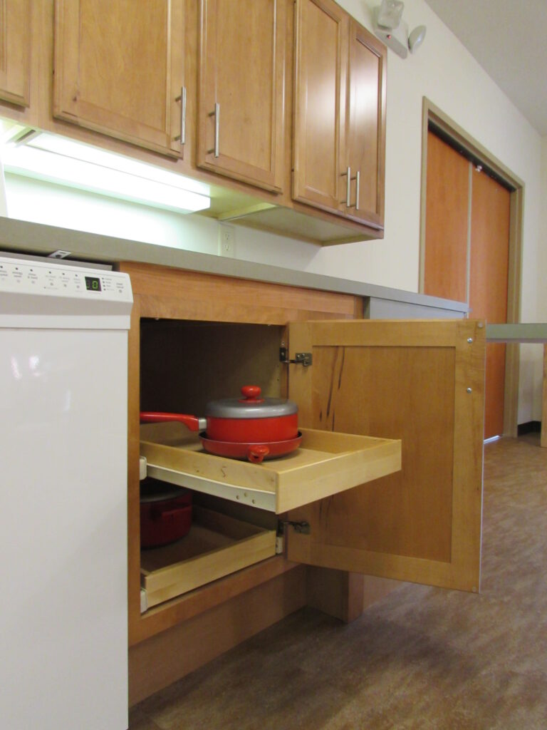 Close up picture of lower cabinet with pull out shelf, pan on shelf.