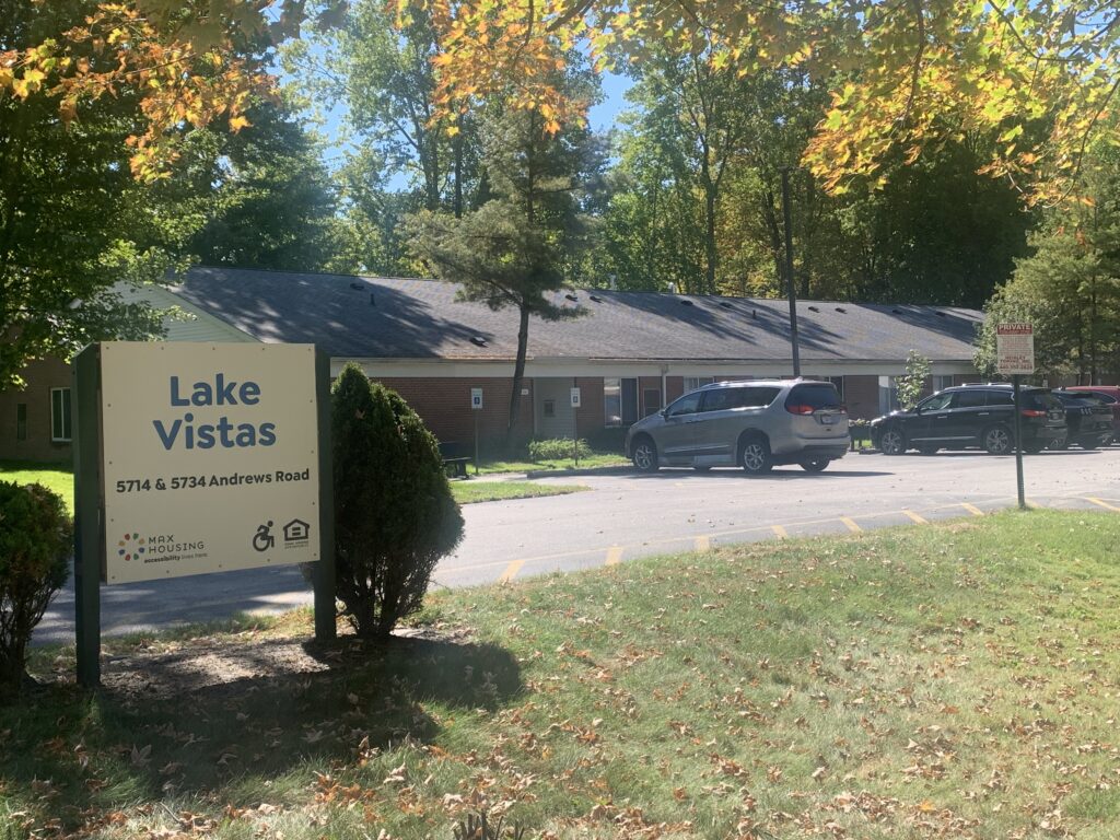 [Image] Picture of Lake Vistas building with Lake Vistas sign to the left of the image. Cars parked in lot.