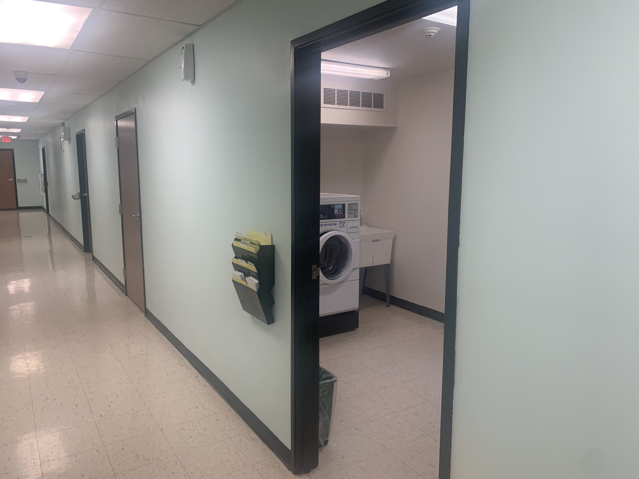 Wide hallways with view into open laundry room with front loading machines.