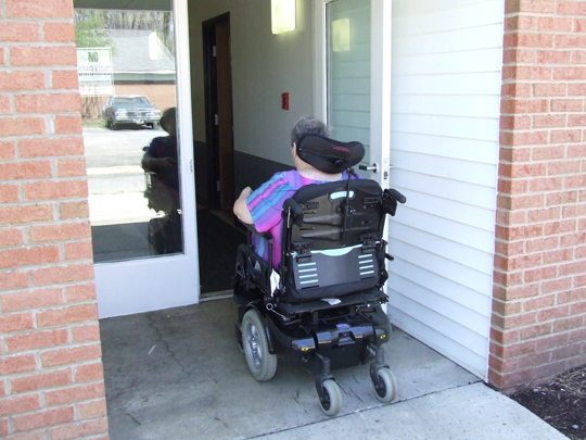 Person in electric wheelchair going through open door into Lake Vistas.