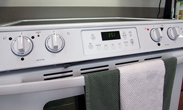 Smooth top range with front controls. Bump dots around controls, with green and white hand towels hanging from door handle.