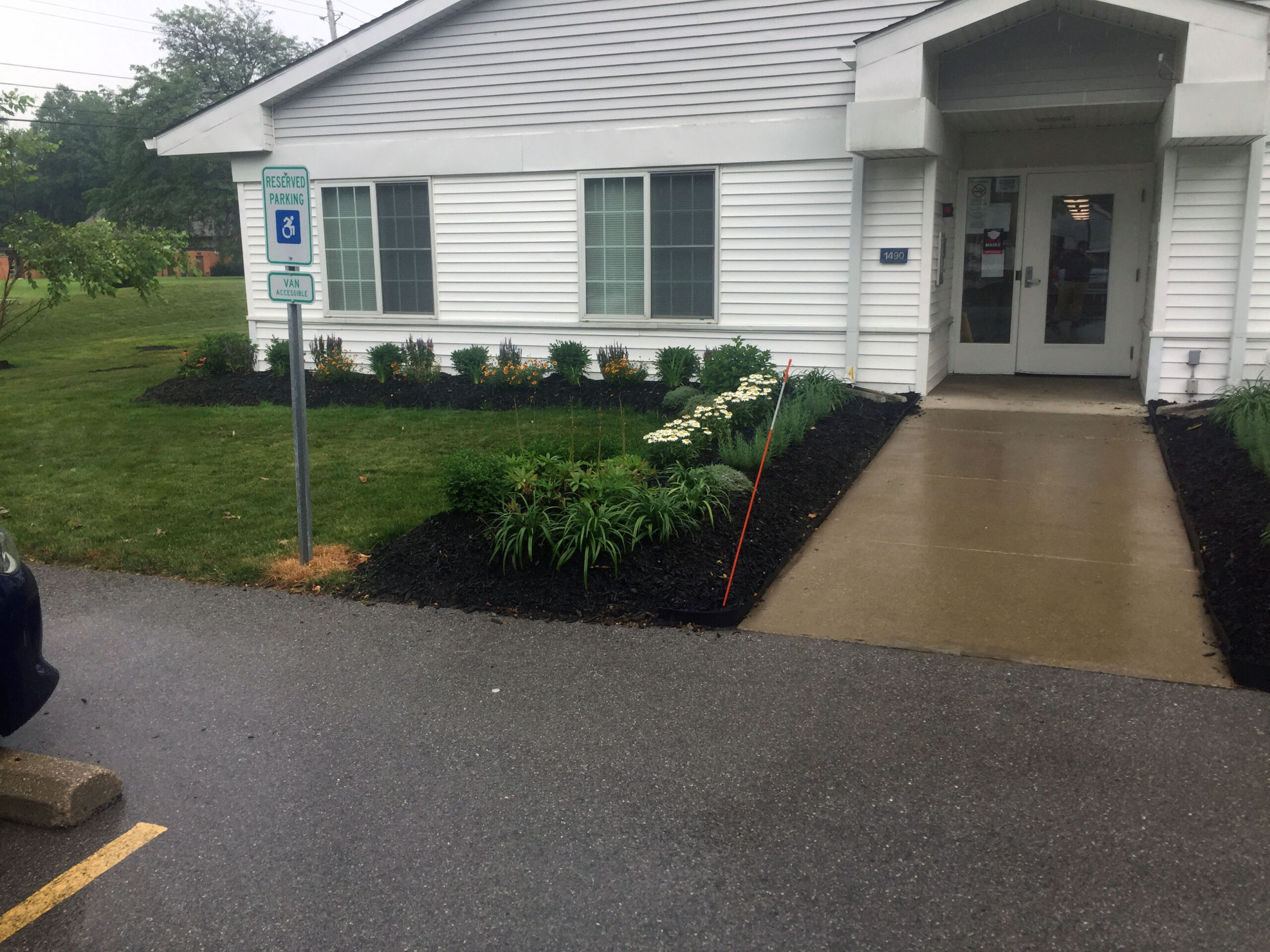 Wide sidewalk to door of Sheffield Vistas. Greenery on the left.